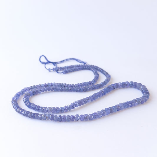 Authentic Tanzanite gemstone beads arranged on a strand, highlighting premium colour and clarity.