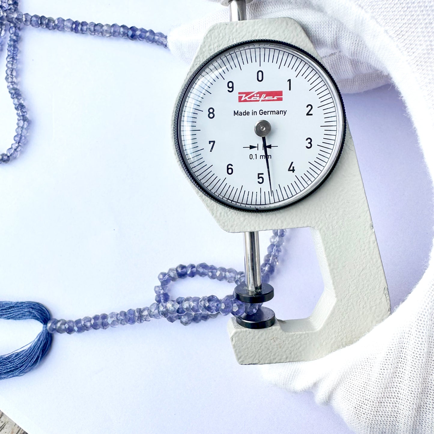 A dial gauge measures the Tanzanite faceted rondelle 4.5-4.7mm gemstone.
