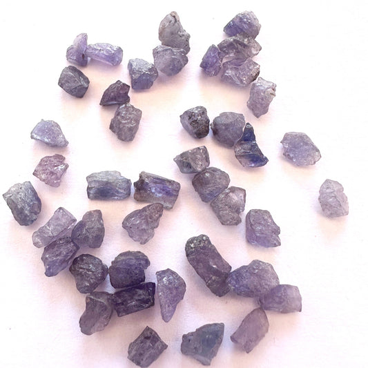 Close-up of Tanzanite rough stones arranged in a 42-piece collection with varied sizes.