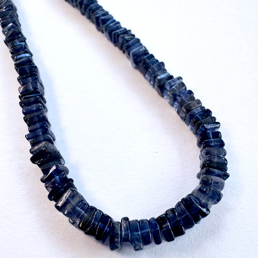 Close-up of polished 4.5mm Tanzanite stone beads with precise square cut.
