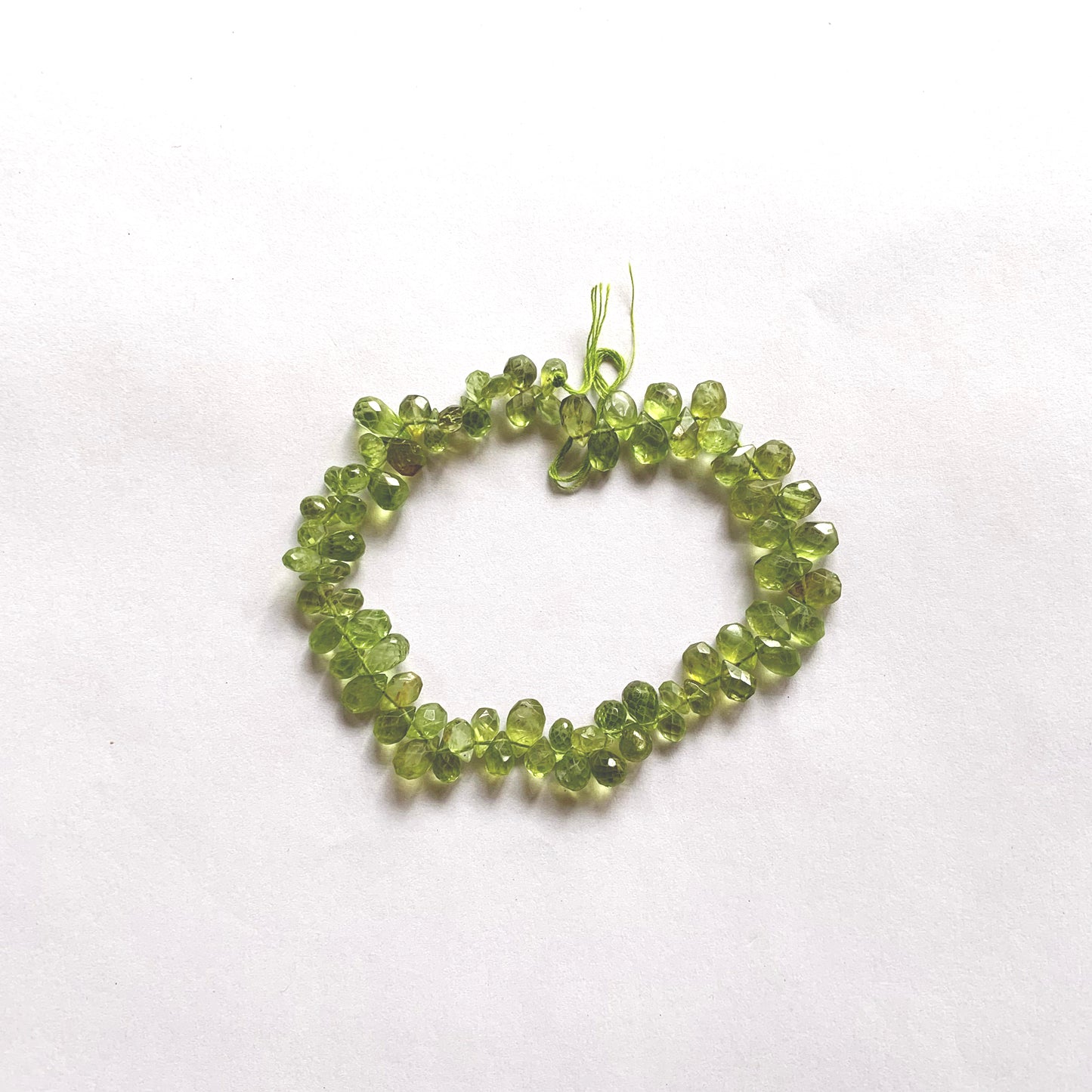 Vibrant green faceted Peridot pear-shaped briolette beads on a 20cm strand with eye-catching sparkle.