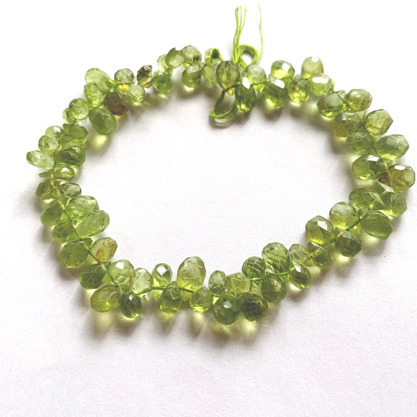 A dial gauge measures the Peridot pear-shaped briolette 4–5.5mm gemstone.