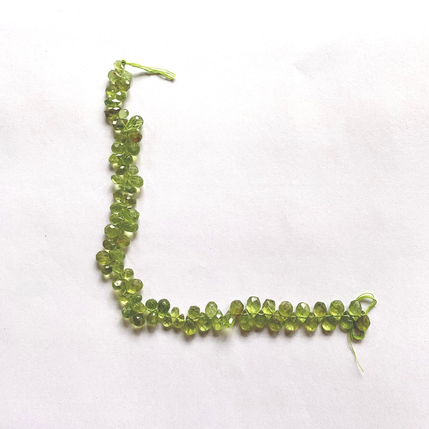 Faceted Peridot teardrop beads strung uniformly to highlight consistent size and shine.