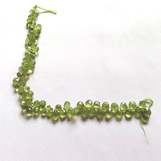 Close-up showcasing the pear-shaped Peridot briolette cut and luminous green hue.