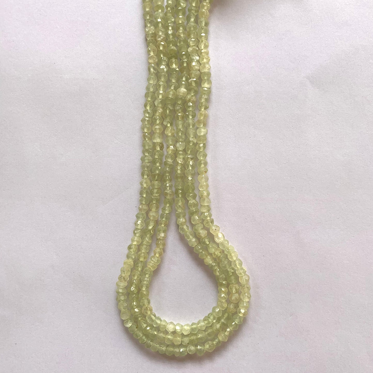 Macro shot of Prehnite beads highlighting their clarity, symmetry, and subtle green glow.