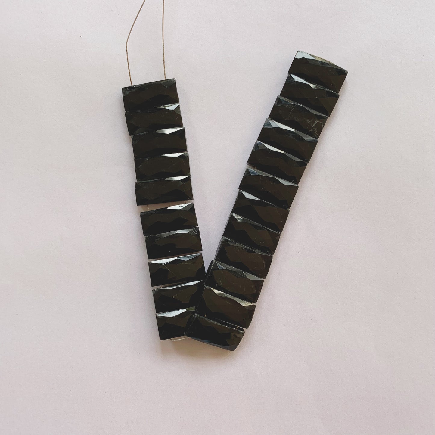 Jet-black faceted rectangle onyx beads in 20mm by 9mm size strung on a 20cm strand for jewellery making.