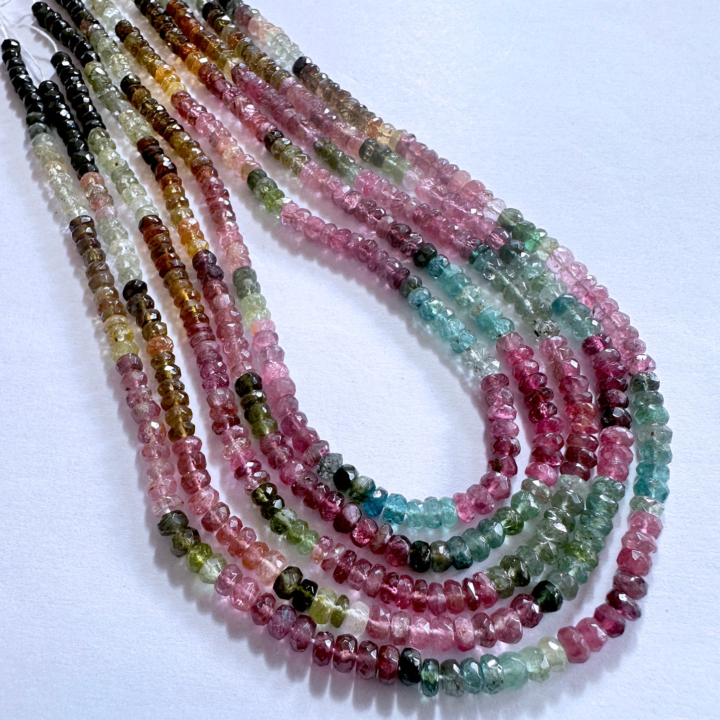 Natural Tourmaline rondelle beads with faceted surfaces, aligned neatly in a strand to highlight their lustrous finish.