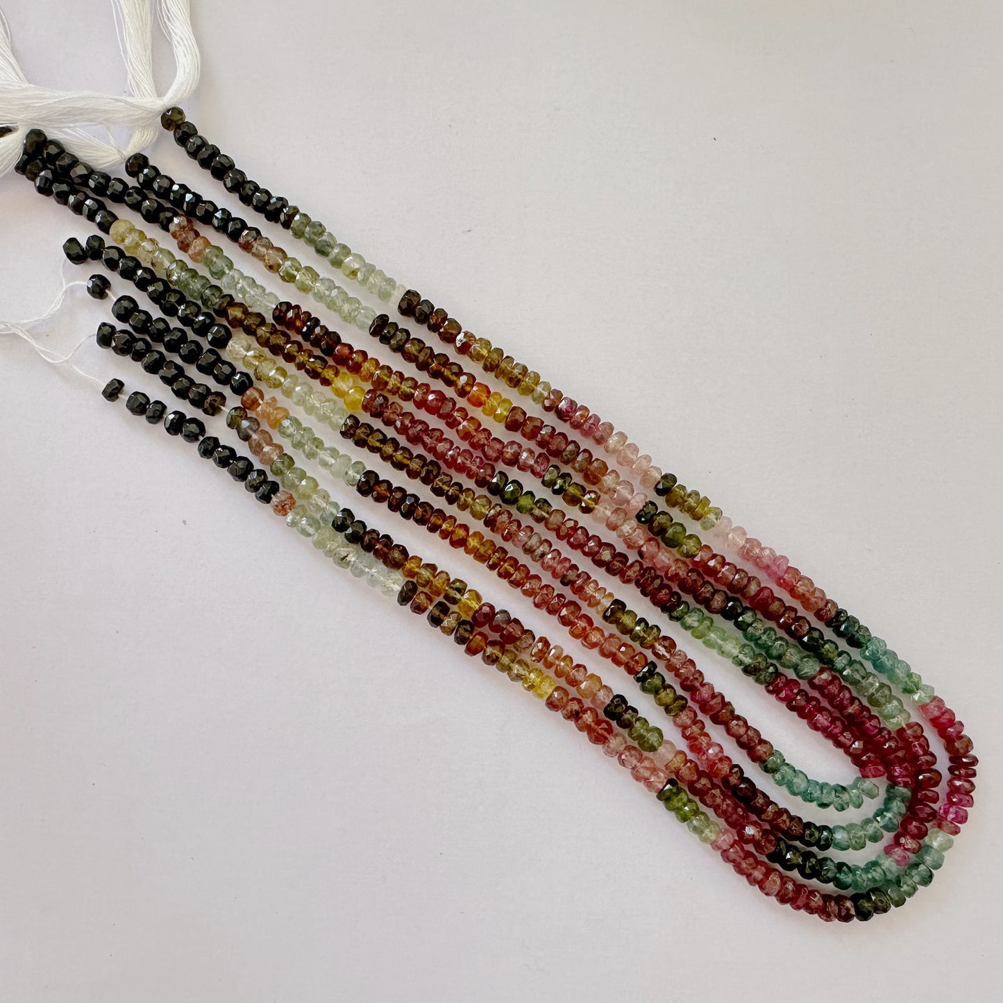 Tourmaline beads in shades of pink, green and black with crisp faceted surfaces.