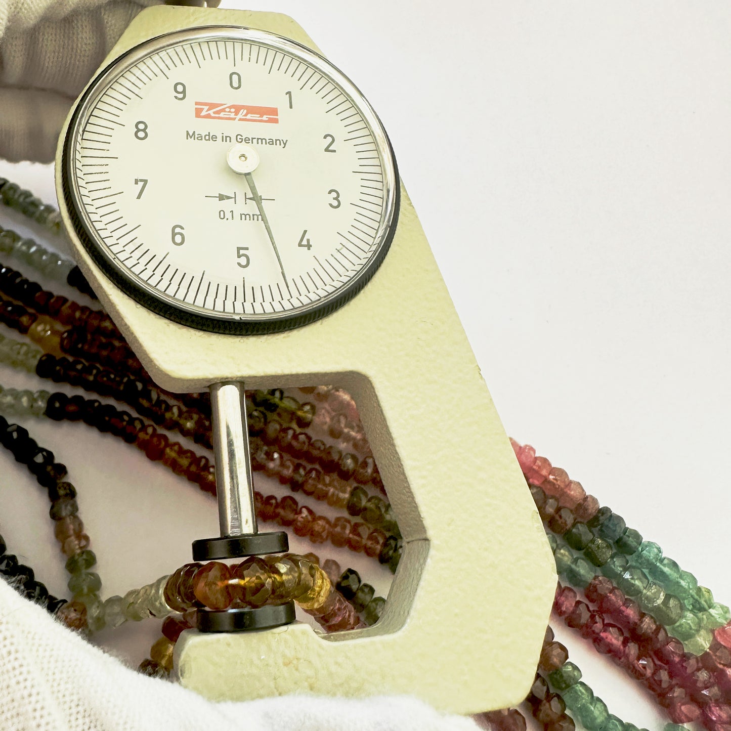 A dial gauge measures the Tourmaline faceted rondelle 4.5mm gemstone.