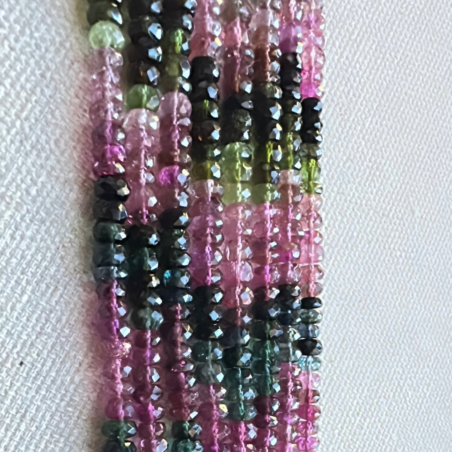 Close-up of faceted tourmaline rondelle gemstones showing crisp cuts and radiant hues under natural lighting.