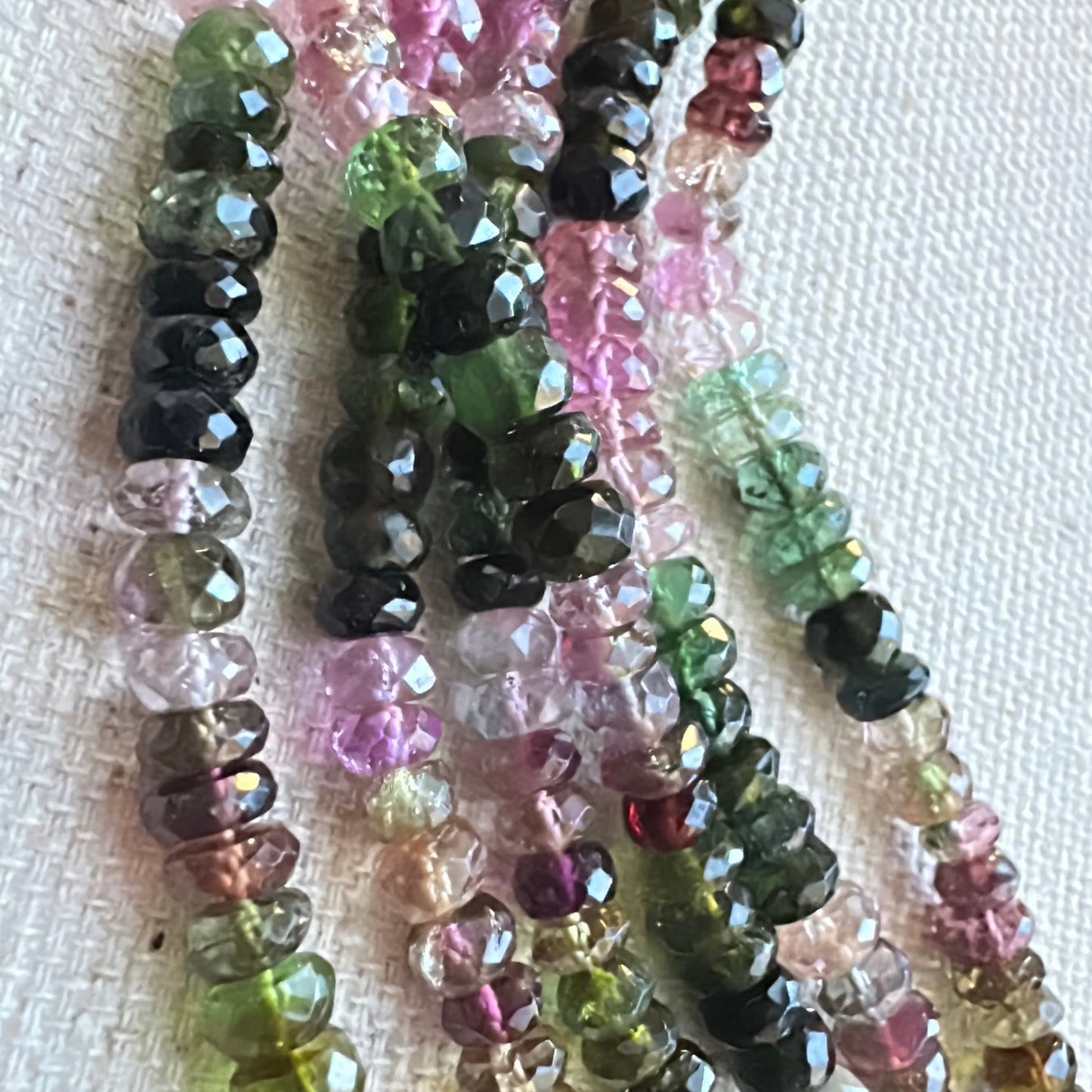 Mixed tourmaline rondelle beads in soft pinks, greens, and golds laid out uniformly across the strand.