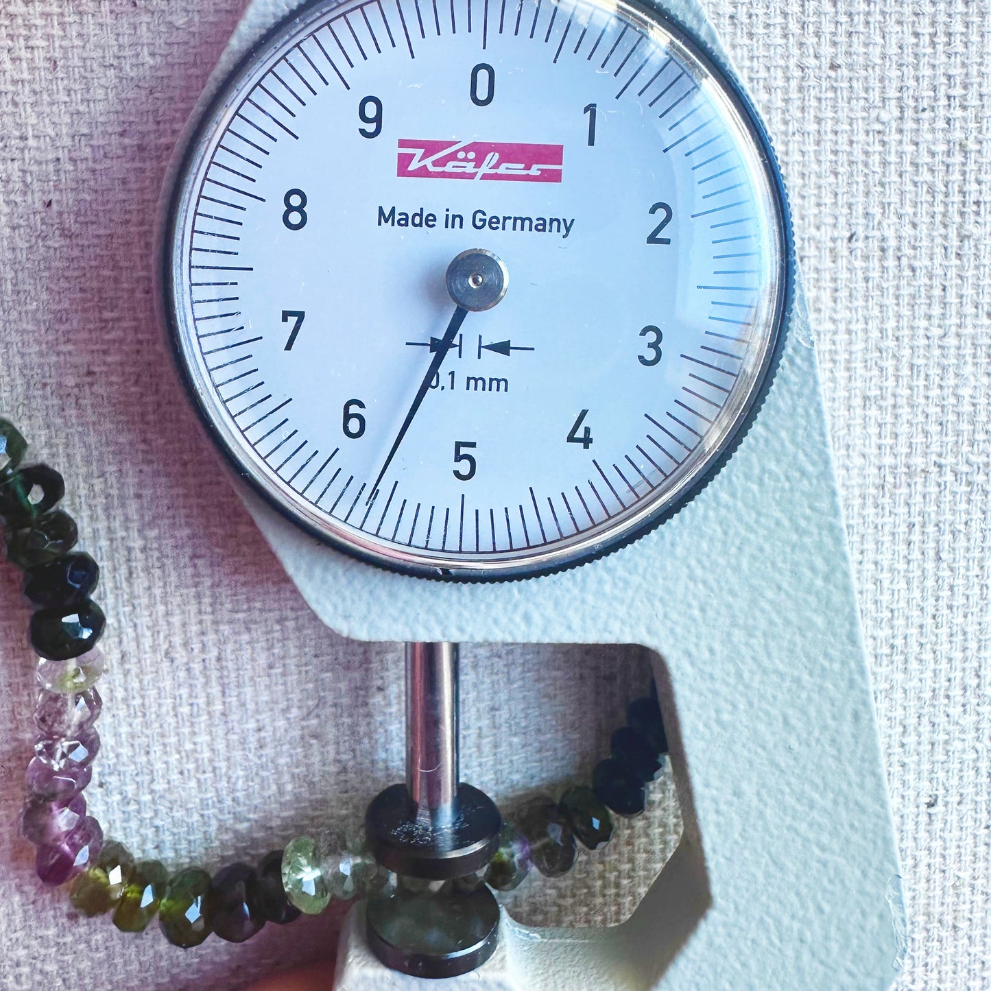 A dial gauge measures the tourmaline faceted rondelle 4.8mm–5.7mm gemstone for size accuracy.
