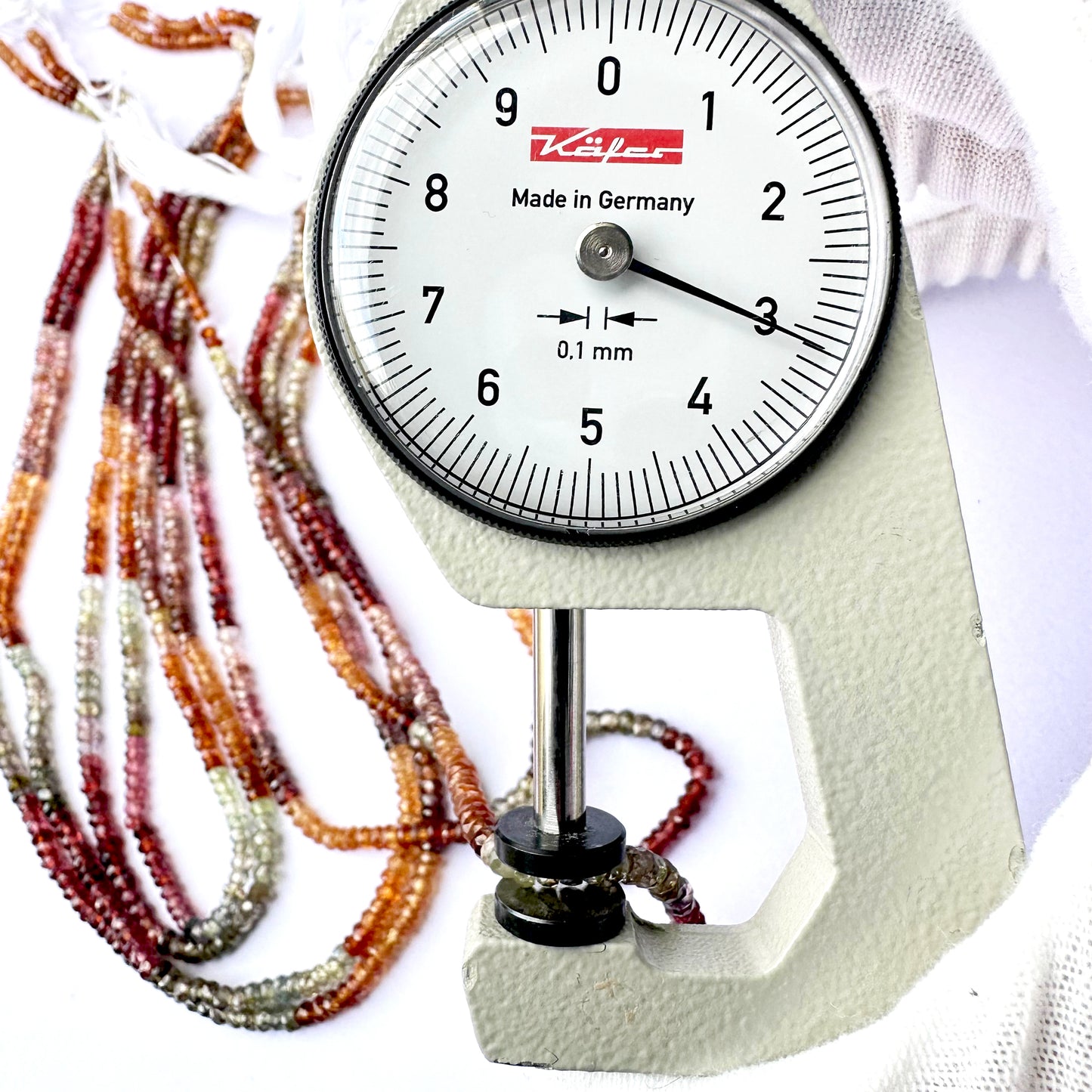 A dial gauge measures the Tundra Sapphire faceted rondelle 3mm gemstone.