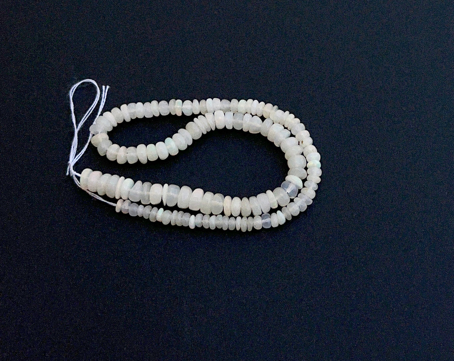 Close-up of natural gemstone beads highlighting smooth rondelle shape and opal glow.