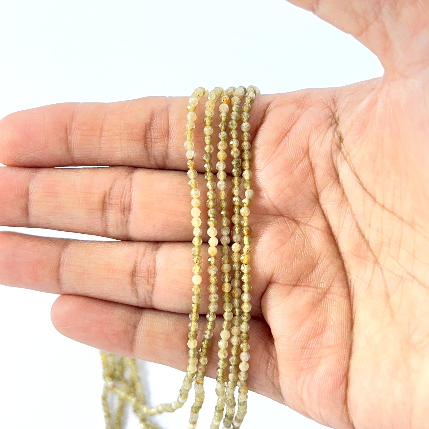 Hand holding high‑quality Yellow Opal gemstone strand featuring uniform 2.4mm faceted rondelles.