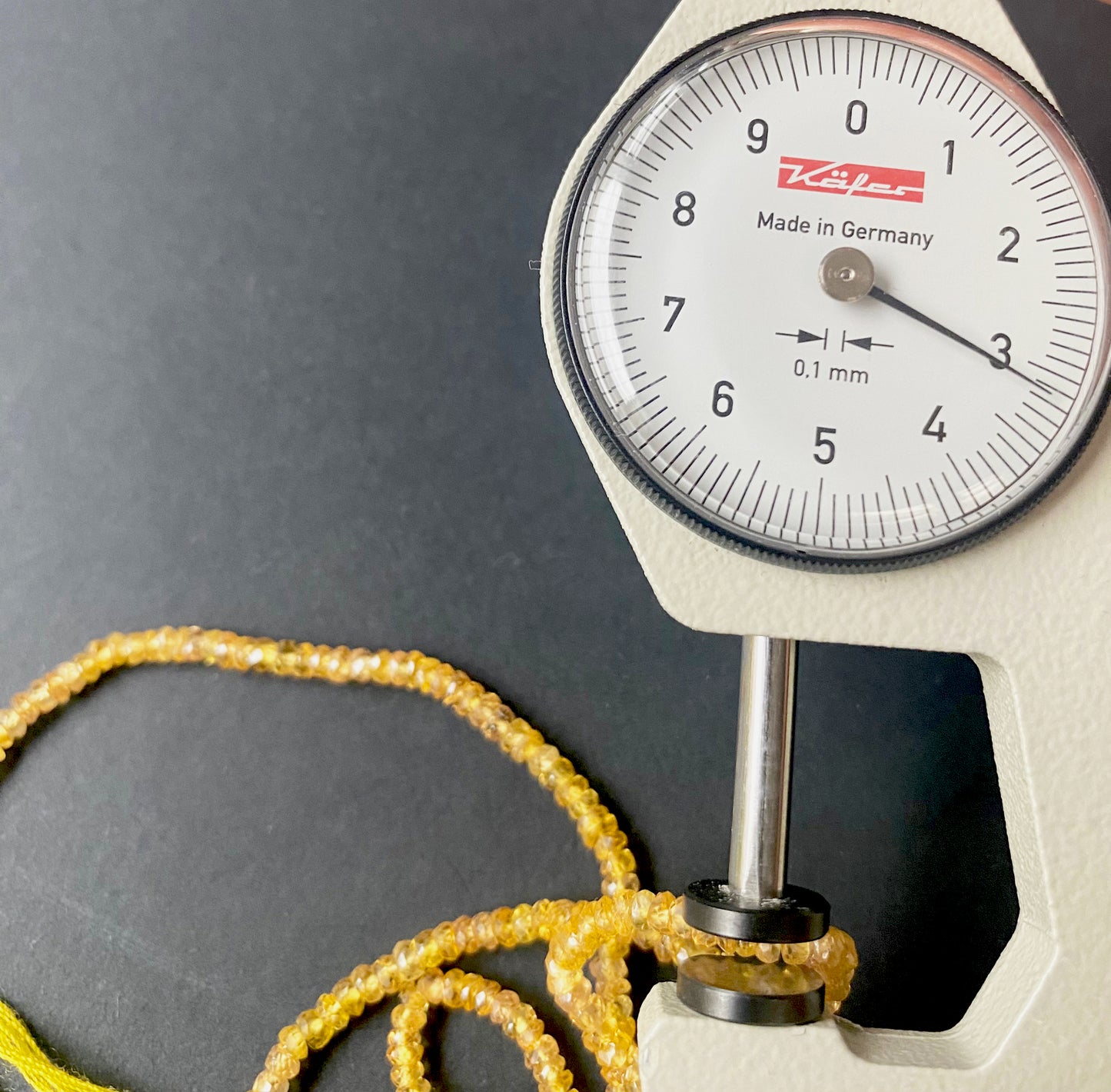 A dial gauge measures the Yellow Sapphire faceted rondelle 2.9–3.2mm gemstone for detail accuracy.