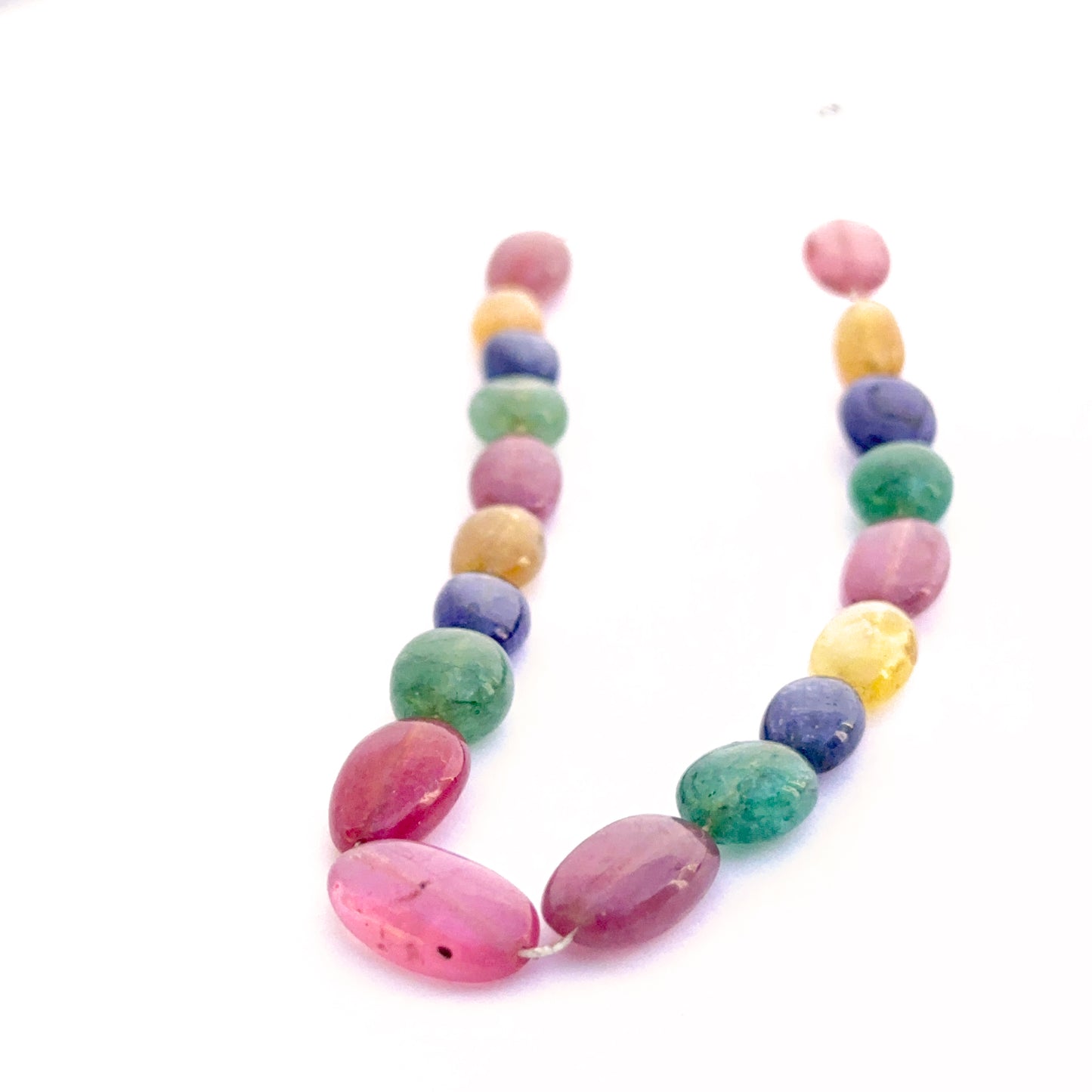 Smooth oval yellow sapphire, blue sapphire, ruby and emerald beads arranged to display uniform shape and rich hues.
