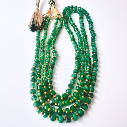 Close-up of faceted rondell emerald beads, 202 carats, highlighting clarity and natural gemstone brilliance.