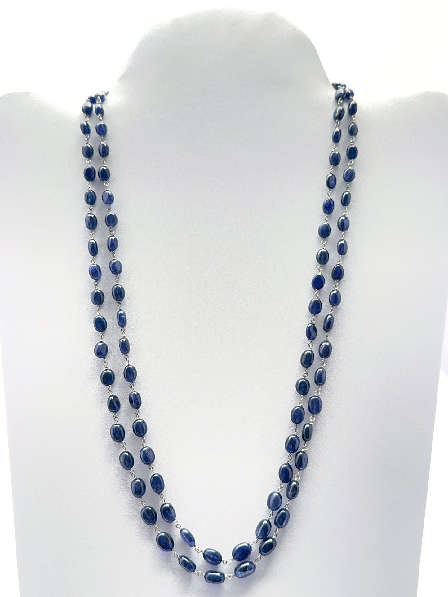 Two‑strand blue sapphire necklace featuring smooth oval beads in deep midnight blue tones.