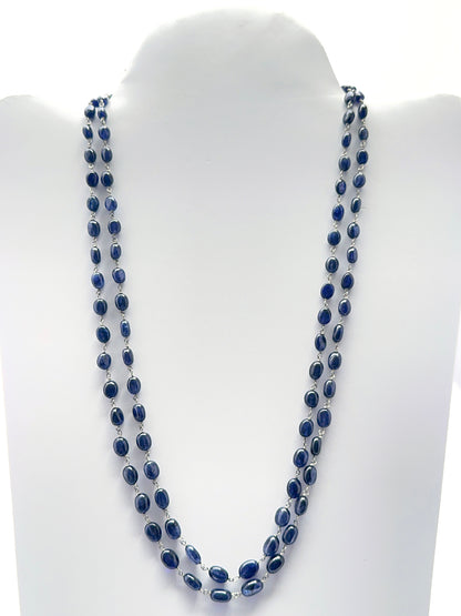 Two‑strand blue sapphire necklace featuring smooth oval beads in deep midnight blue tones.
