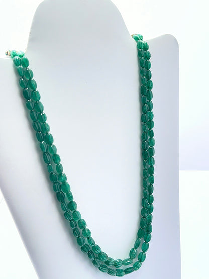 Emerald necklace with carved oval beads showing deep colour and handcrafted detail.