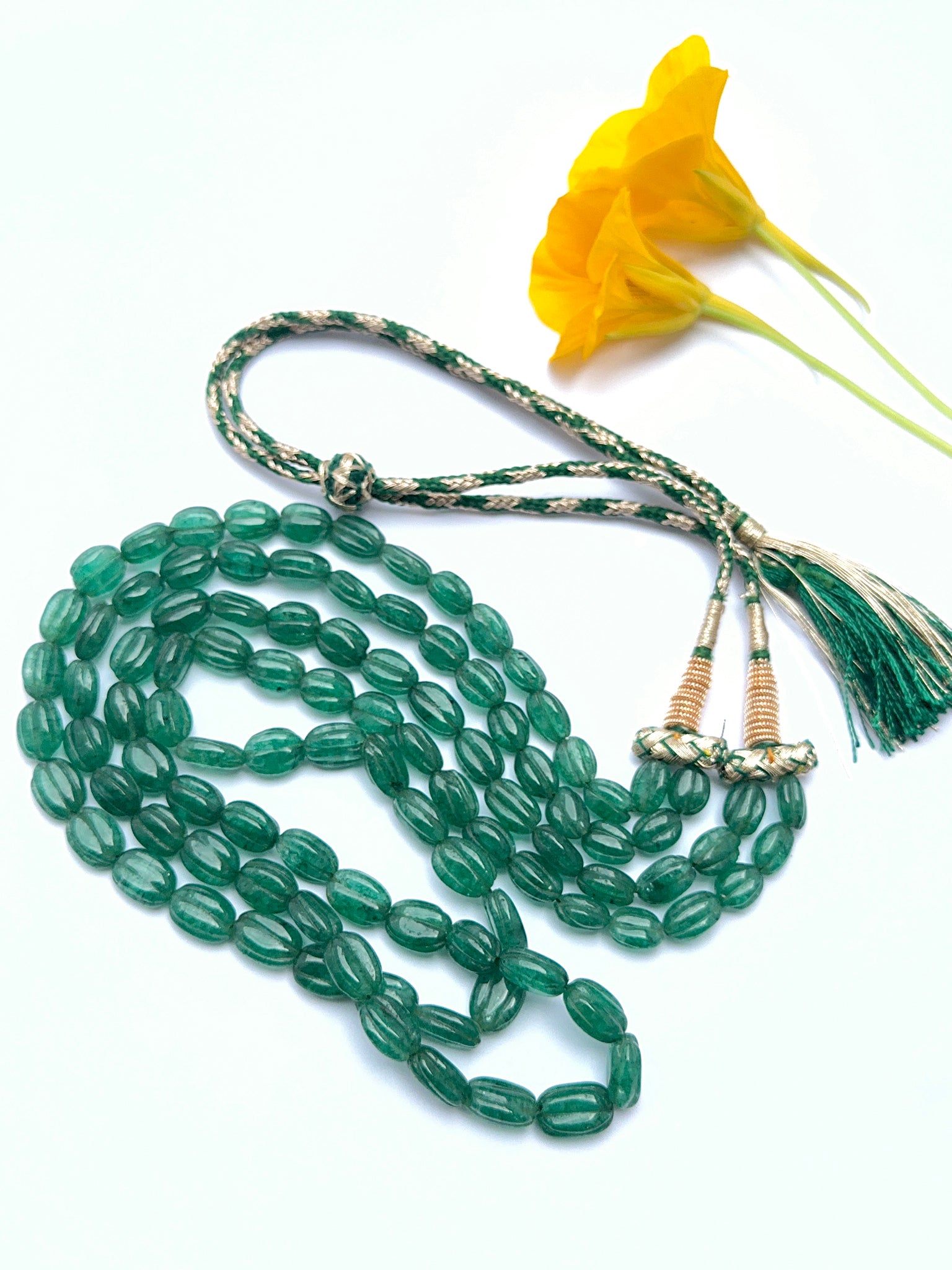 Elegant emerald necklace featuring carved beads in a refined layered design.