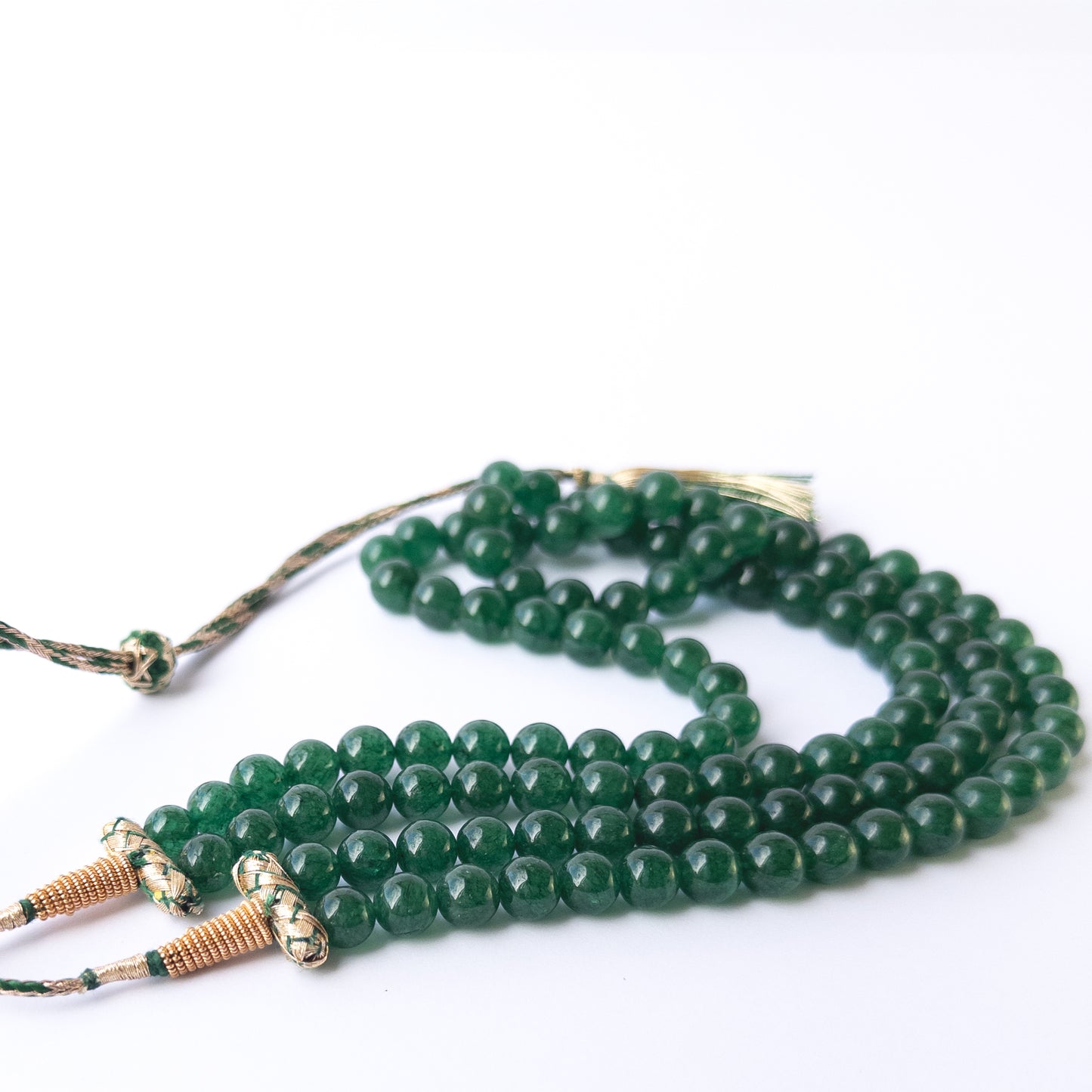 Close up of Emerald gemstone beads showing polished round shapes and vibrant green colour for crafting projects.