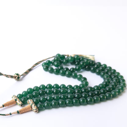 Close up of Emerald gemstone beads showing polished round shapes and vibrant green colour for crafting projects.