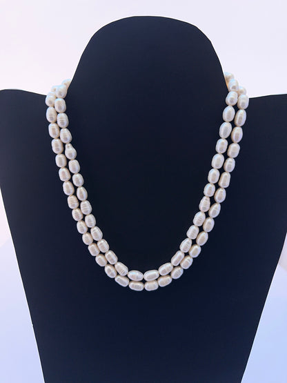 Close‑up of 7.5–8mm textured oval pearls arranged on a polished freshwater pearl necklace.