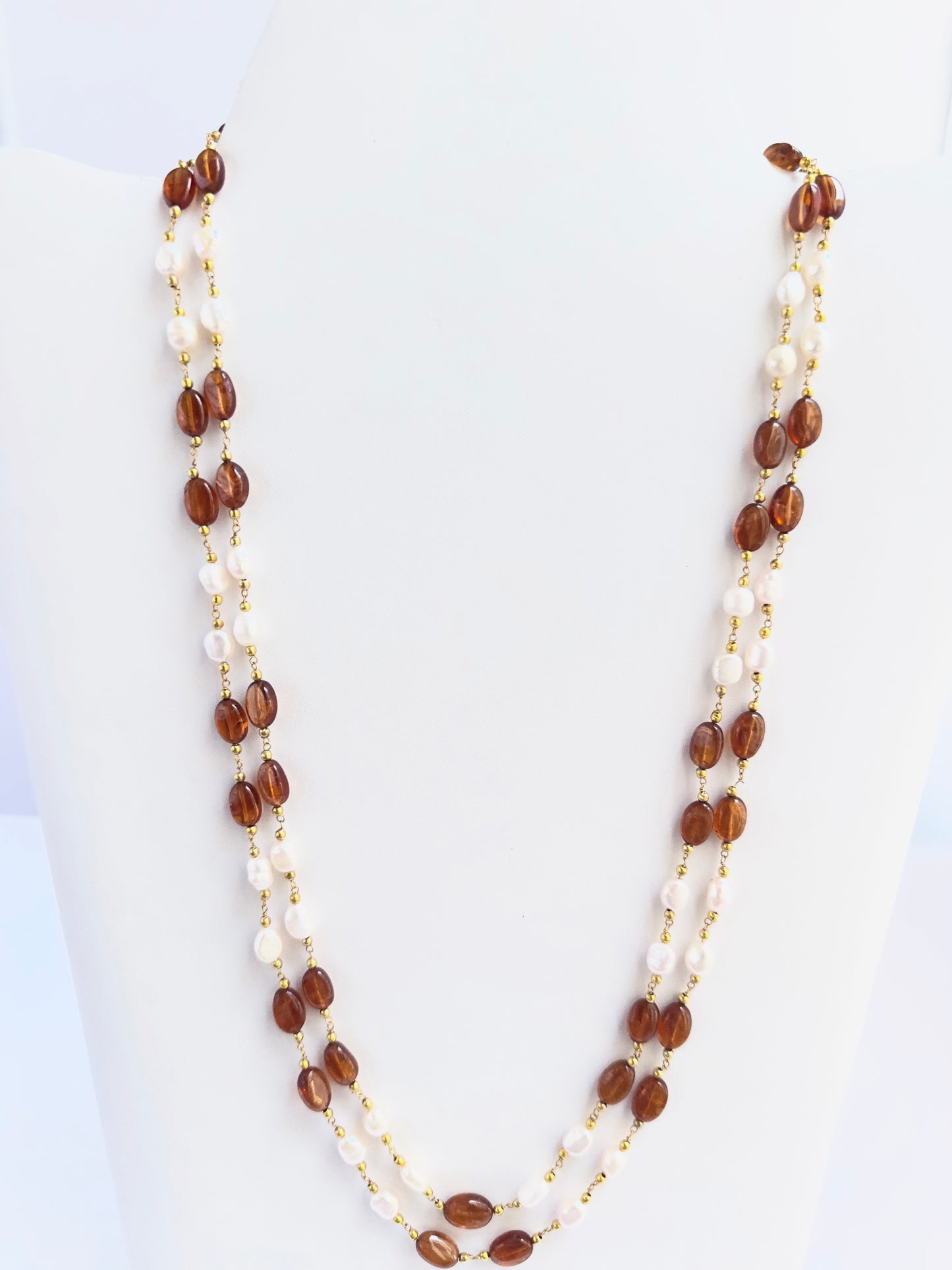 Hessonite and pearl necklace with smooth oval beads, two strands, radiant gemstone contrast.