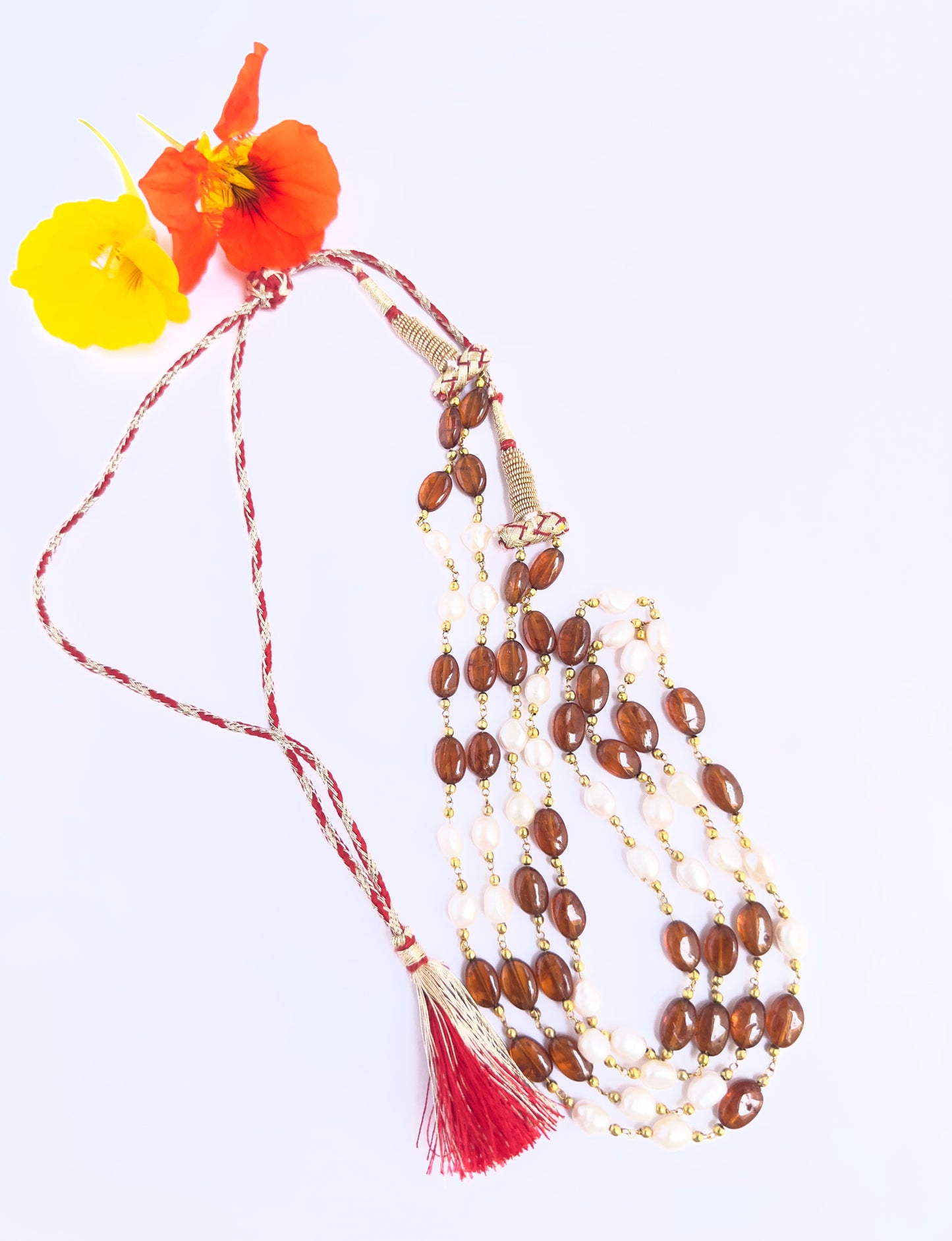 Gemstone beads necklace combining Hessonite and pearls, polished oval cut, radiant shine, silk tassel detail.