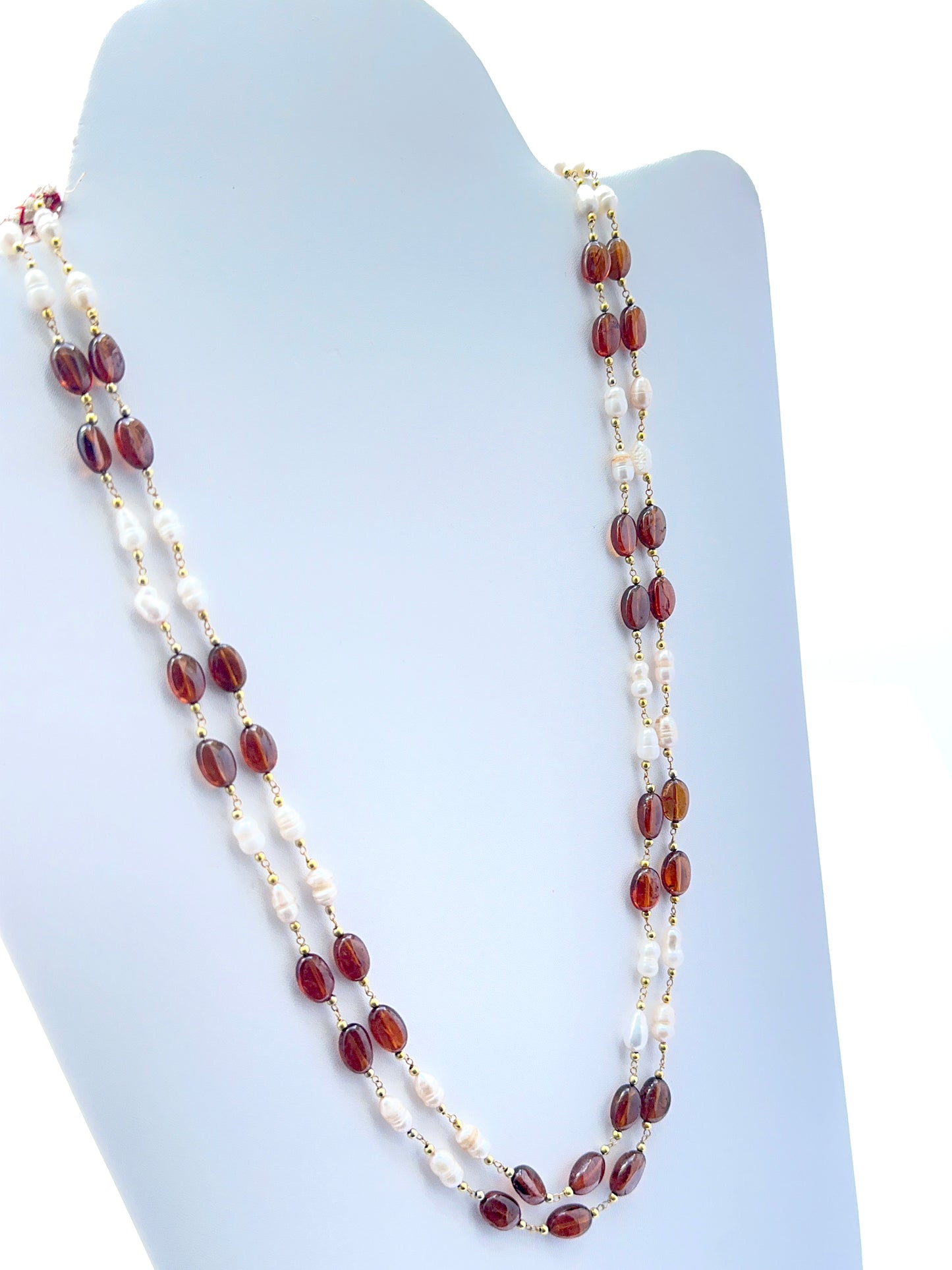 Close‑up of hessonite and pearl beads arranged on a polished two‑strand necklace.
