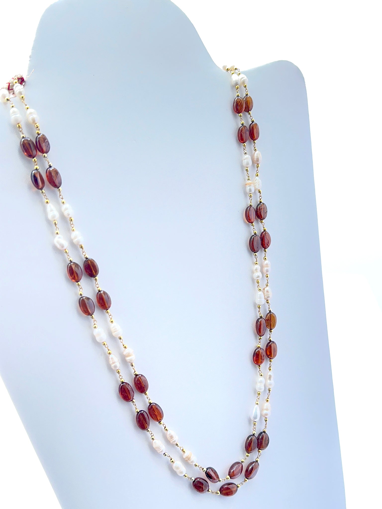 Close‑up of hessonite and pearl beads arranged on a polished two‑strand necklace.