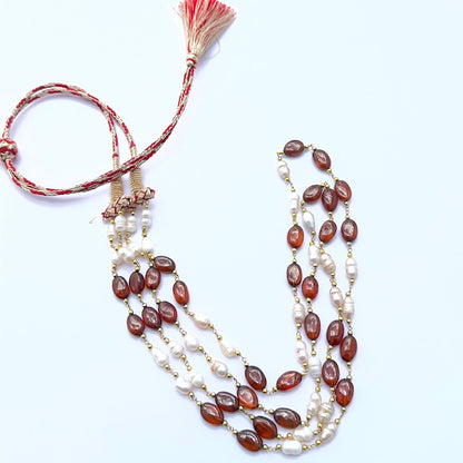 Elegant gemstone necklace featuring hessonite and textured pearls in a layered design.
