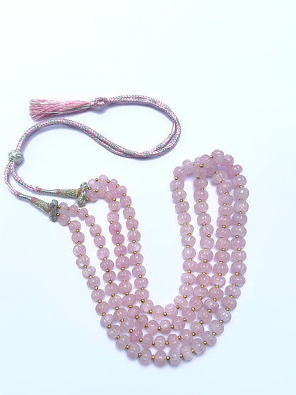 Natural rose quartz necklace with carved beads arranged in a refined two‑strand layout.