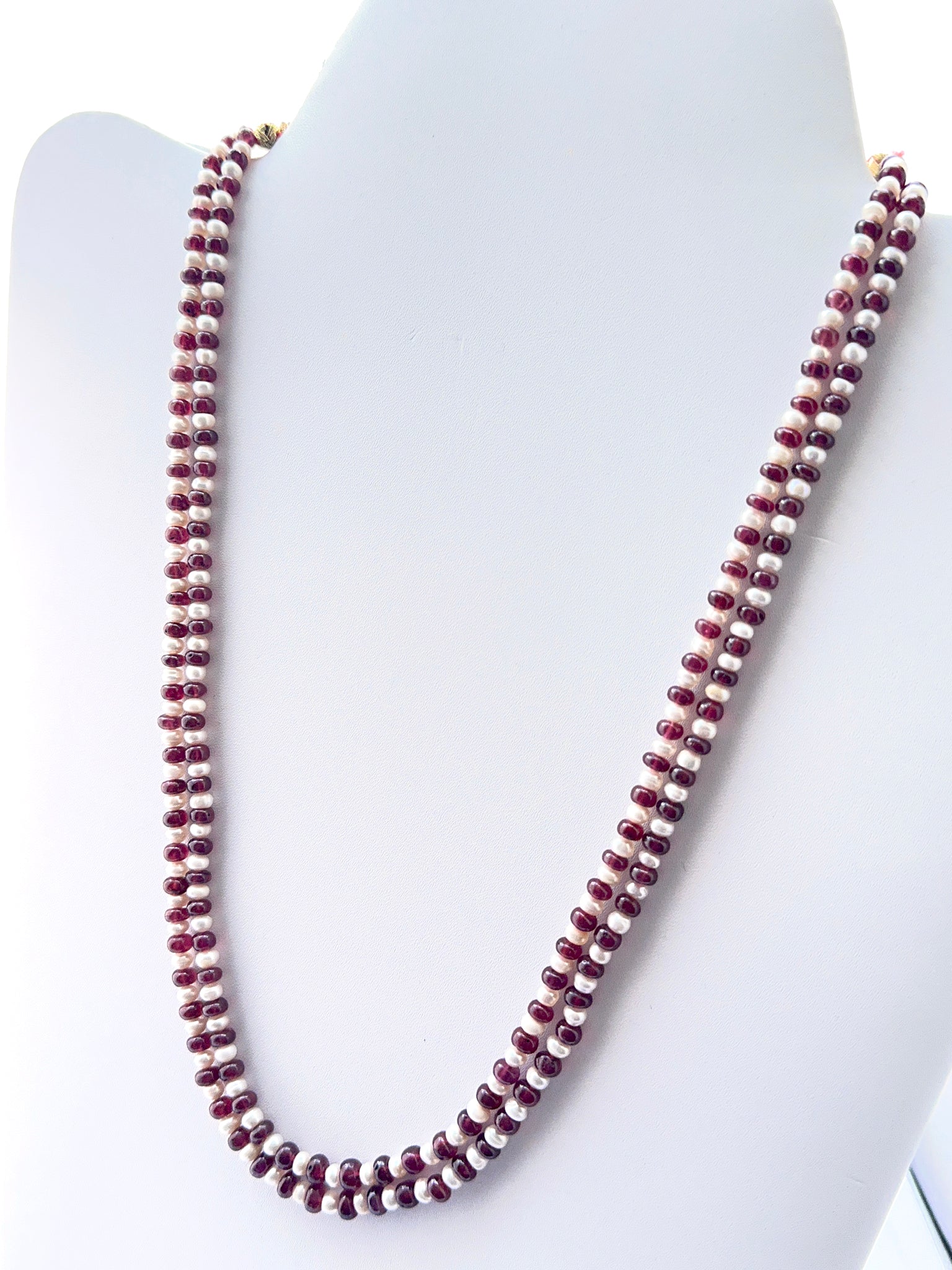 Close‑up of ruby rondelle beads and pearls arranged on a polished necklace.