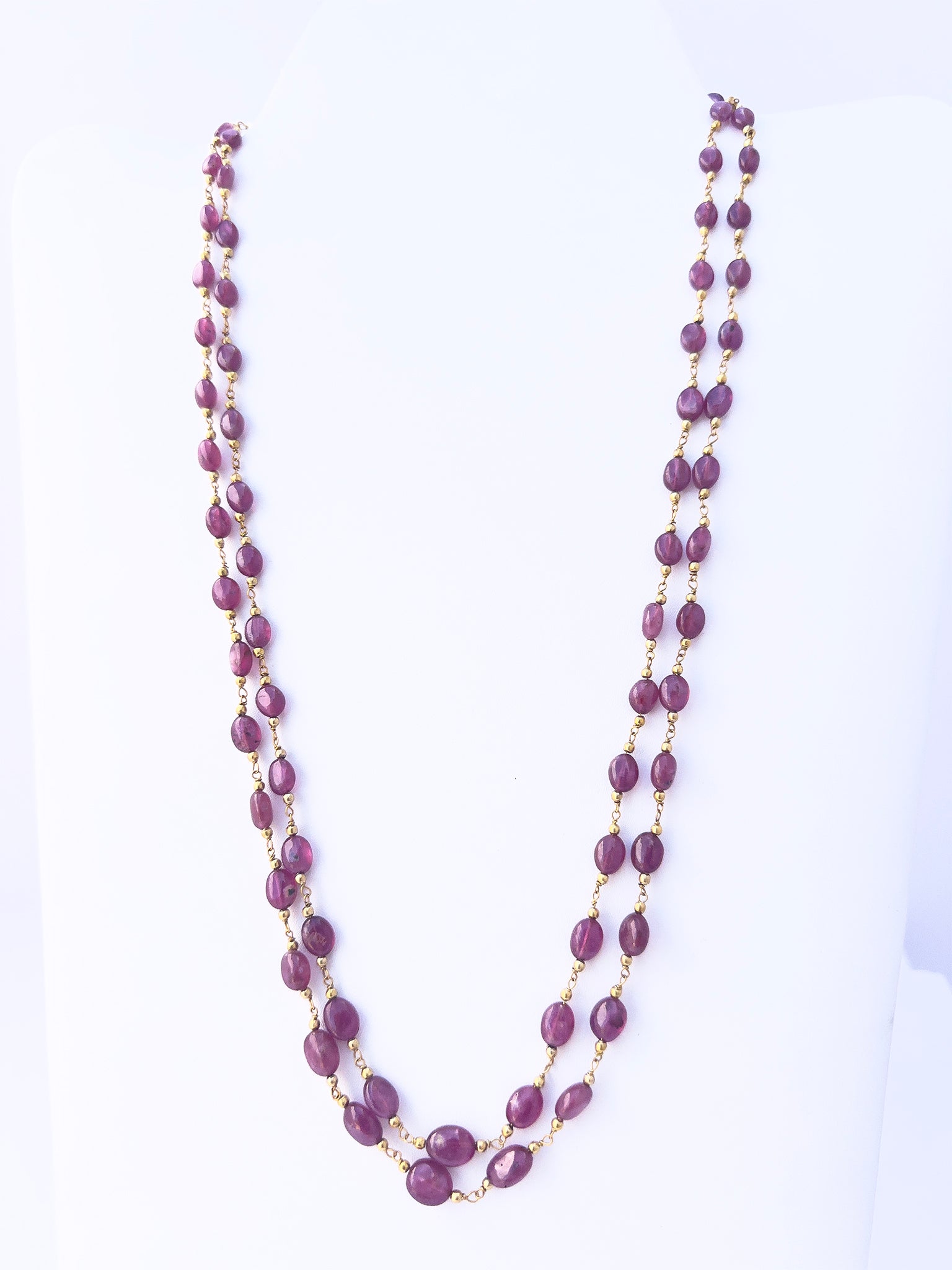 Close-up of Ruby gemstone beads, smooth oval cut, polished finish, arranged in two strands.