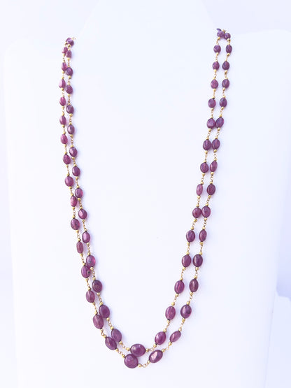 Close-up of Ruby gemstone beads, smooth oval cut, polished finish, arranged in two strands.