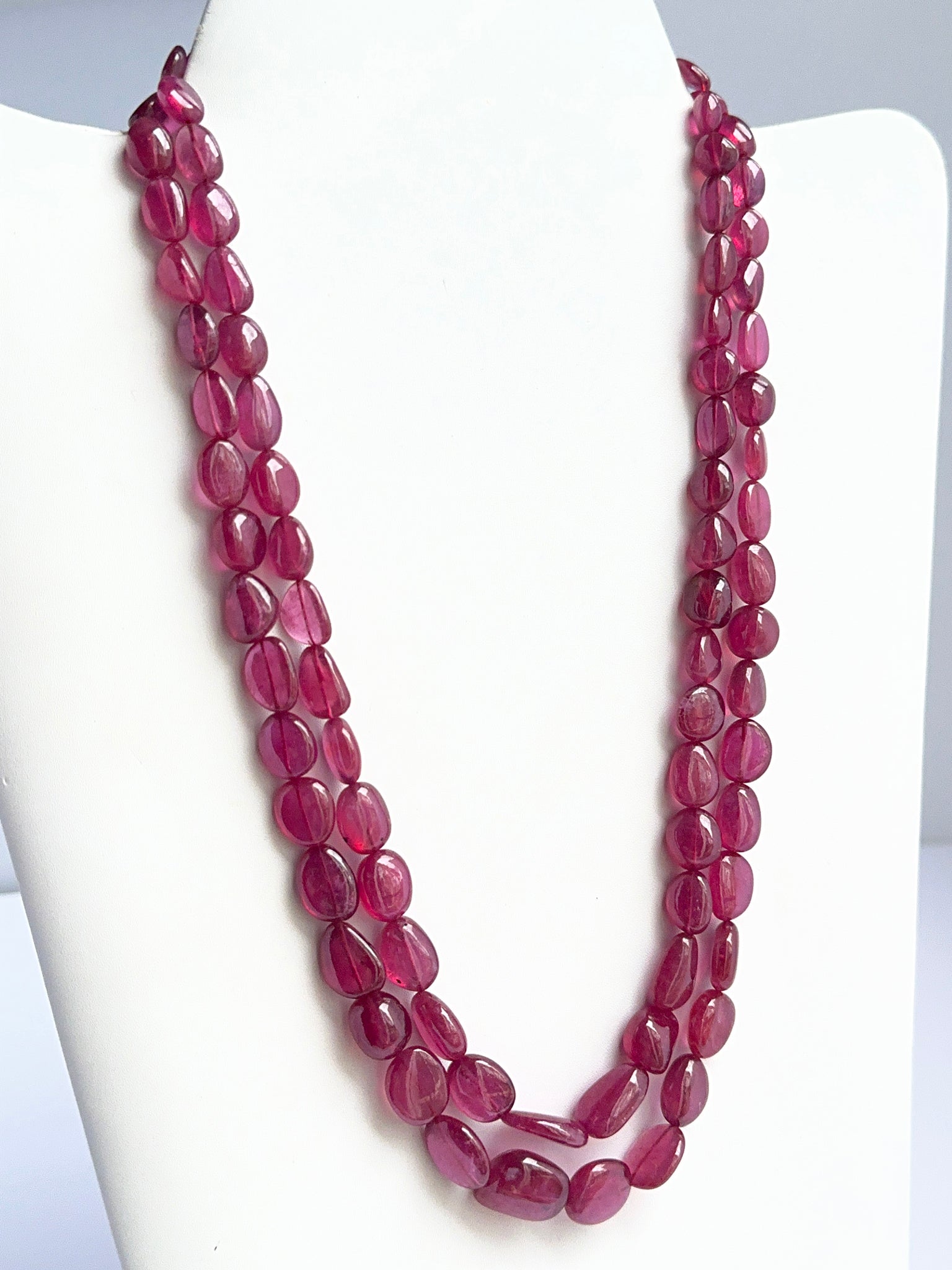 Close‑up of polished tumble ruby beads arranged on a finished ruby necklace.