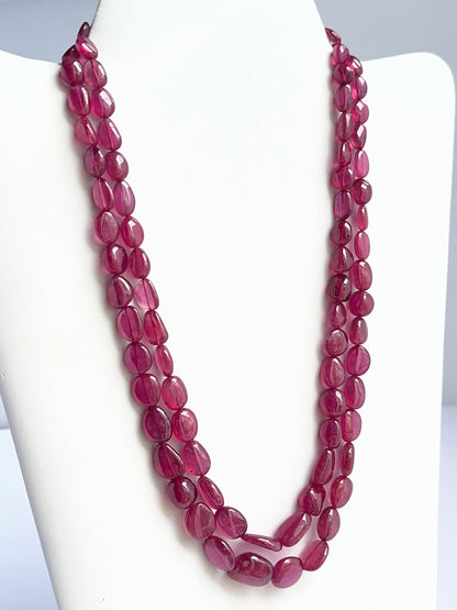 Close‑up of polished tumble ruby beads arranged on a finished ruby necklace.