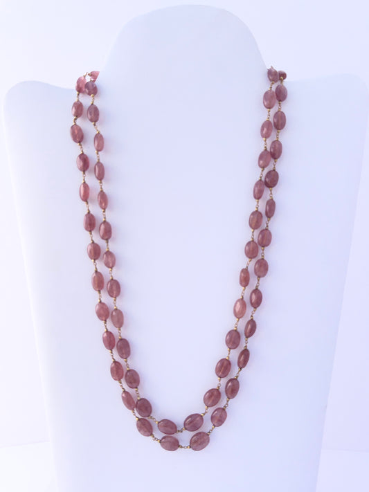 Close-up of Strawberry Quartz gemstone beads, smooth oval cut, polished finish, arranged in strands.