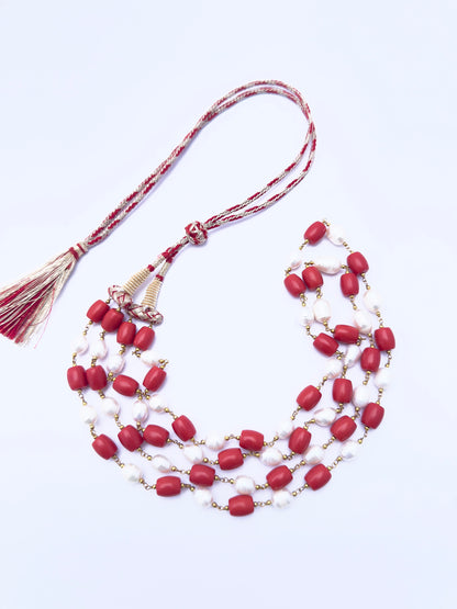 Artisan-crafted necklace featuring coral and pearls, radiant finish, adjustable silk tassel.