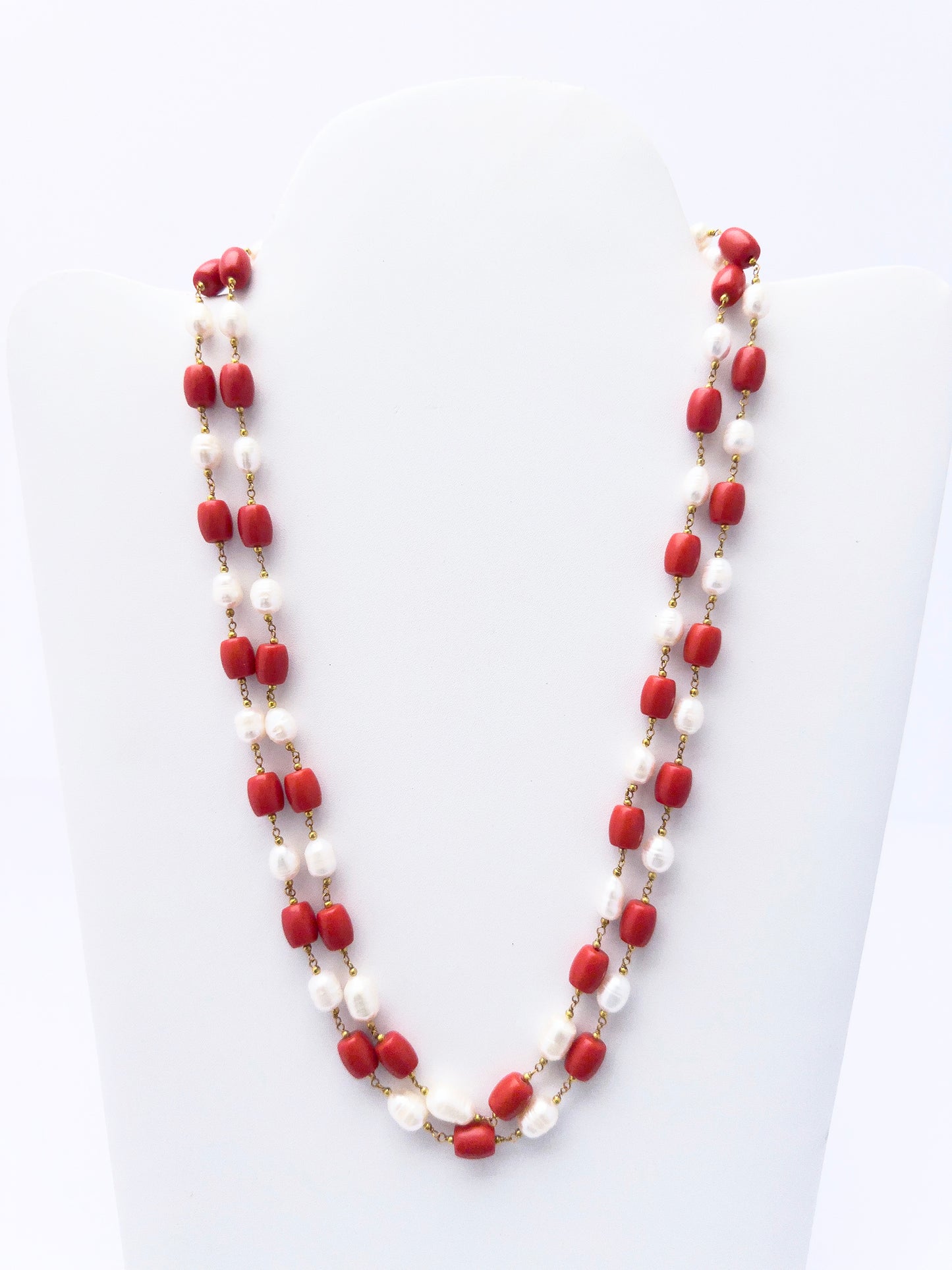 Close-up of Taiwan Coral beads paired with lustrous pearls, polished smooth drum cut, arranged in strands.