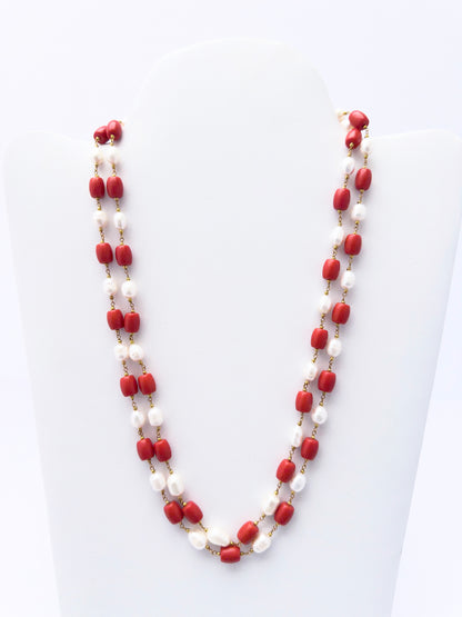 Close-up of Taiwan Coral beads paired with lustrous pearls, polished smooth drum cut, arranged in strands.
