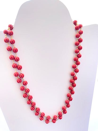 Close‑up of carved coral pumpkin beads arranged on a polished necklace.