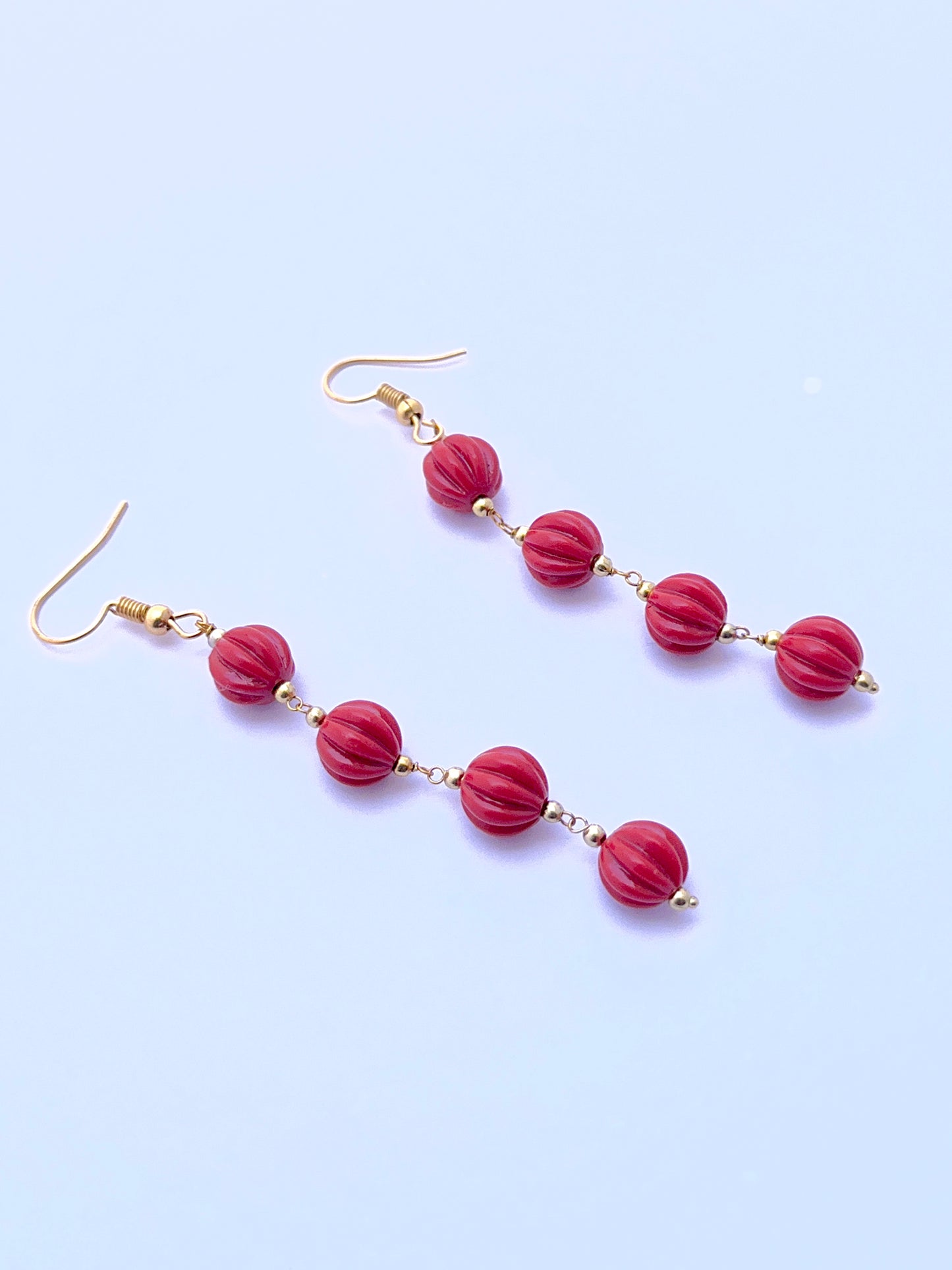 Natural coral earrings with carved beads arranged in a refined two‑strand layout.
