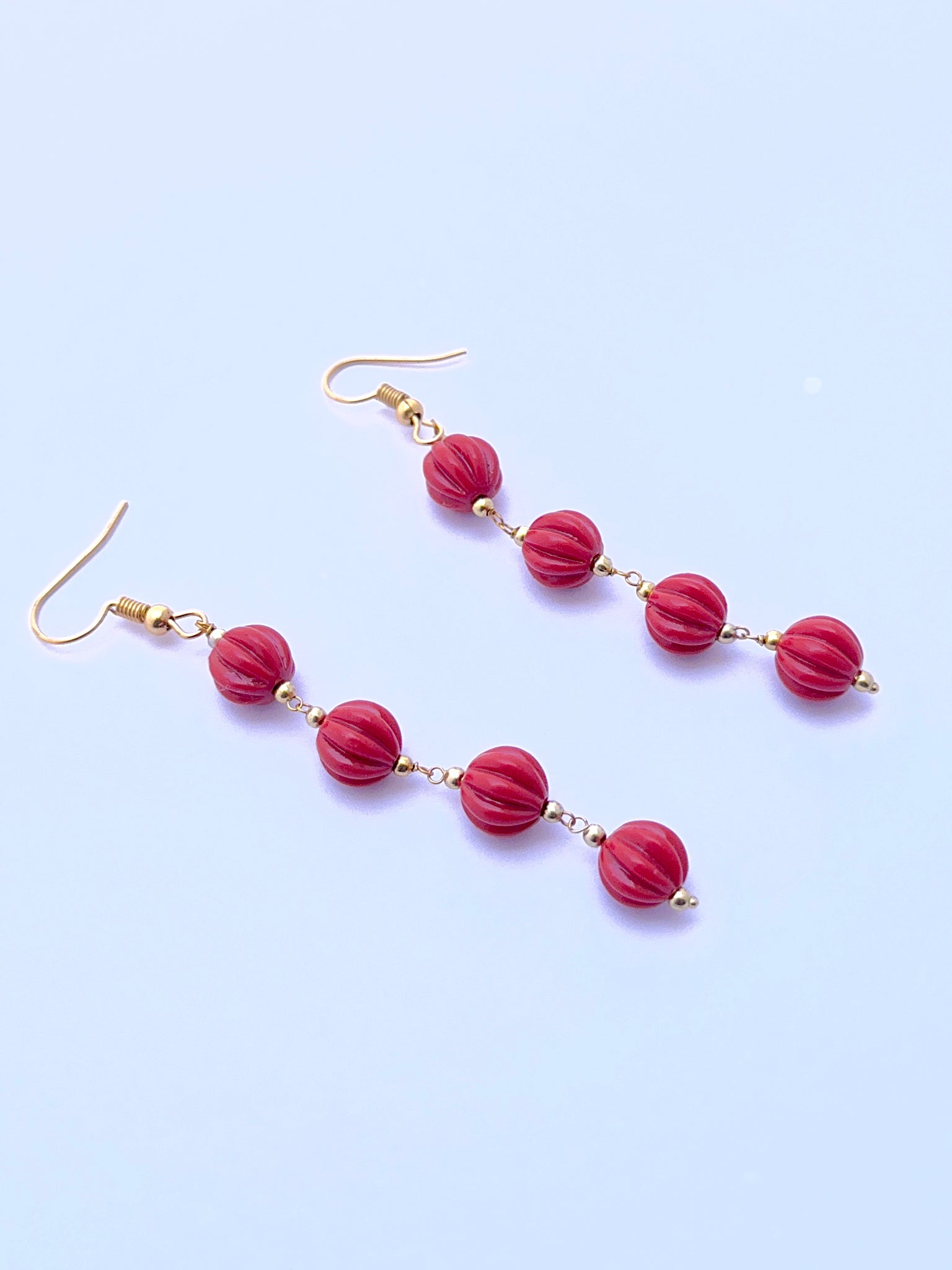 Natural coral earrings with carved beads arranged in a refined two‑strand layout.