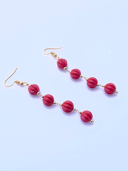 Natural coral earrings with carved beads arranged in a refined two‑strand layout.