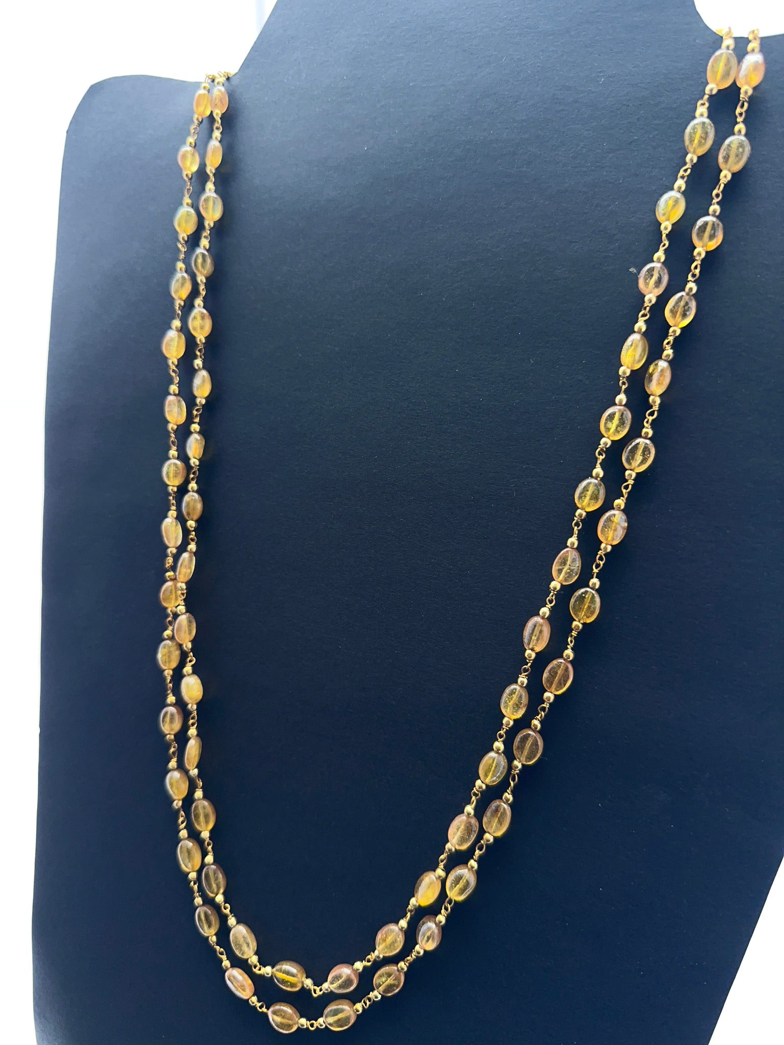 Close‑up of smooth oval yellow sapphire beads arranged on a polished necklace.