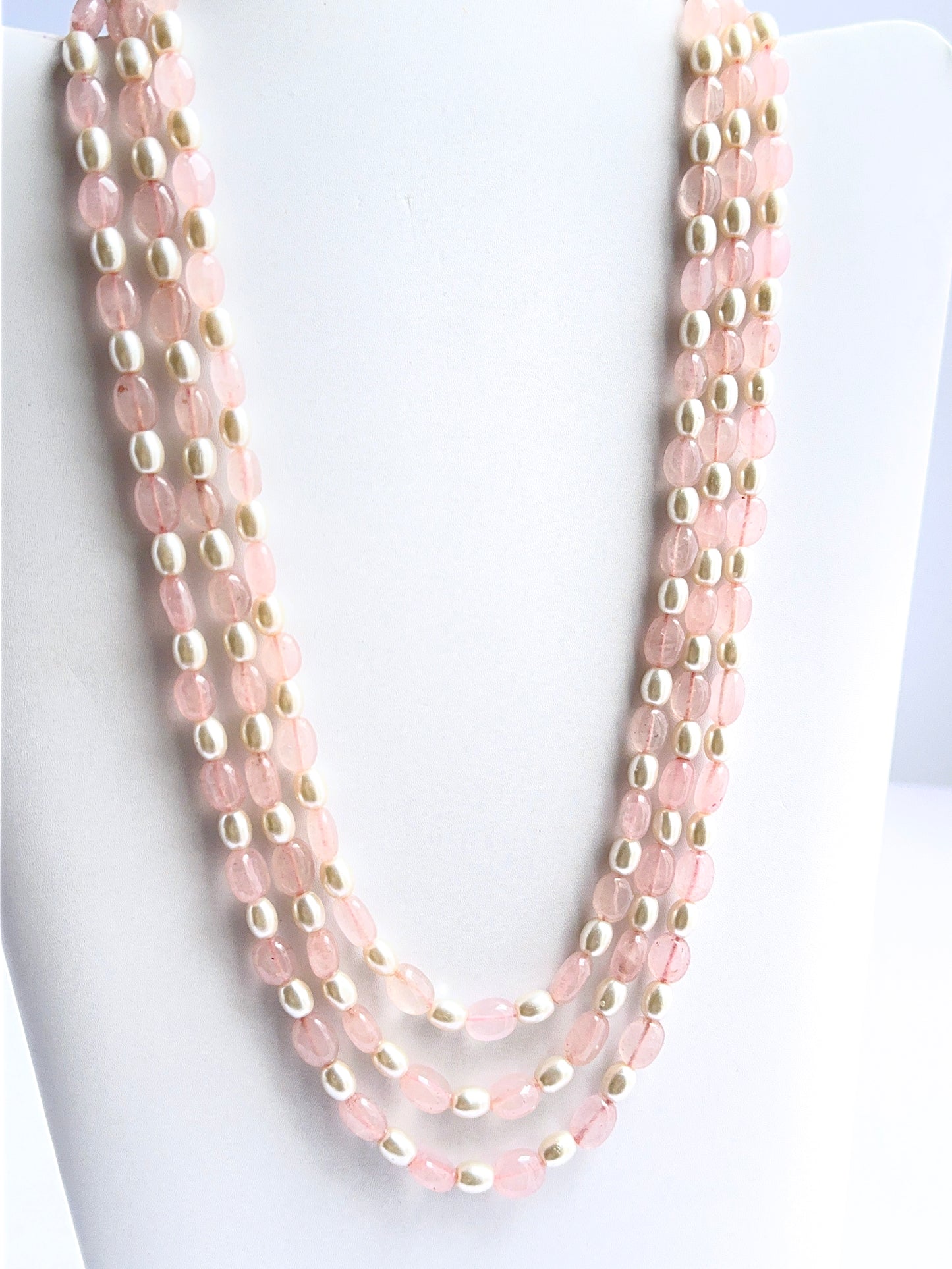 Close‑up of quartz and shell pearl beads arranged on a polished three‑strand necklace.